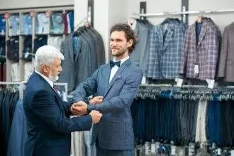 Men fitting fashionable costumes in store
