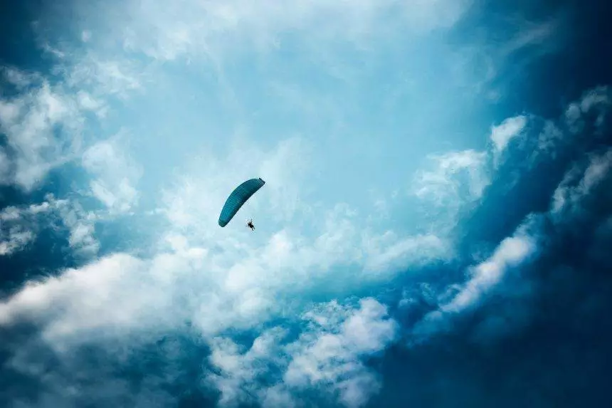 Paraglider flying in the cloudy sky. Extreme activity, hobby and sport